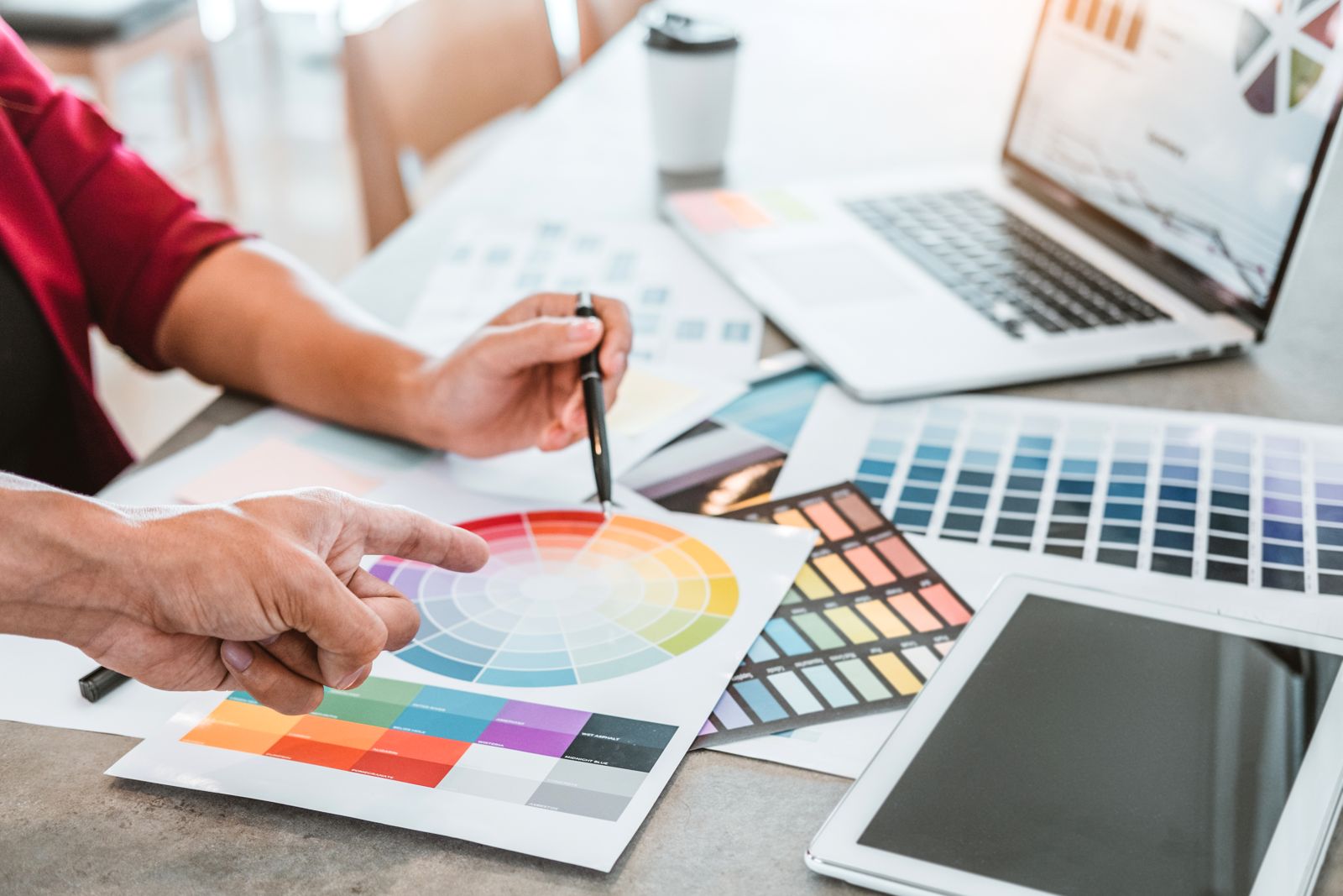 Designers choosing a brand colour palette with a colour wheel and swatches
